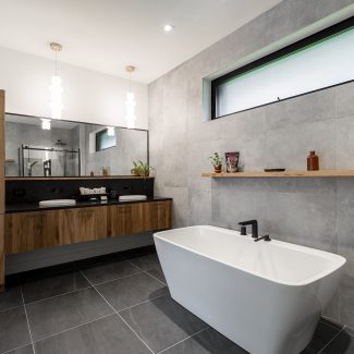 Interior of a modern bathroom with neutral tones and a separate bathtub.