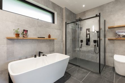 Intérieur d'une salle de bain moderne aux tons neutres avec baignoire et douche séparées.