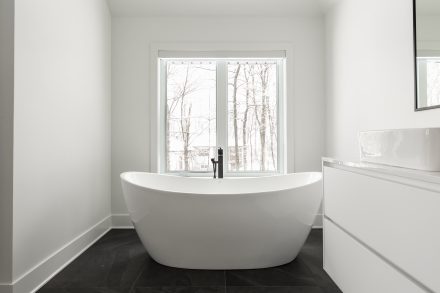 Modern design of a spacious bathroom with shiny white cabinets.