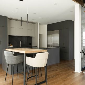 Modern kitchen with dark cental island and subtle lighting.