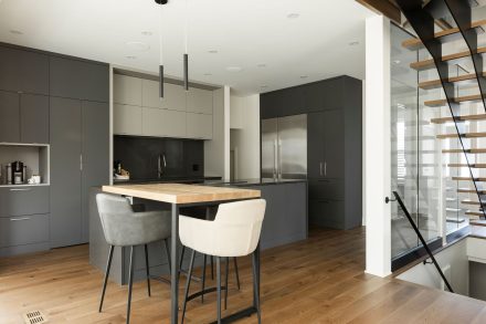 Intérieur de cuisine moderne avec îlot central foncé et éclairage subtil.