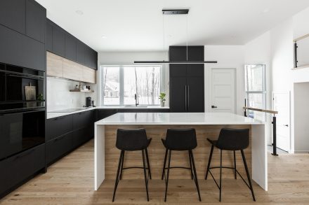 Modern kitchen cabinets in an open space, with a central marble island and refined lighting.