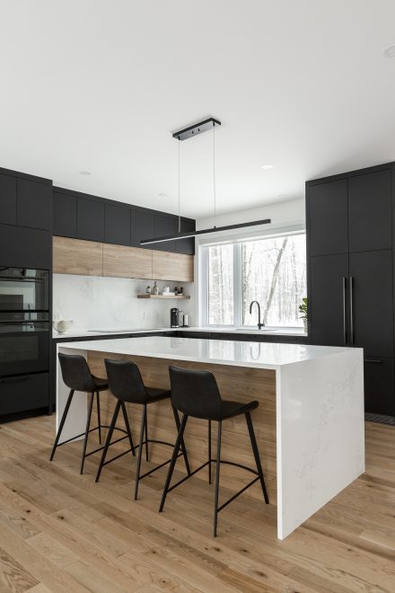 Modern kitchen with central island and custom storage in a renovated townhouse.