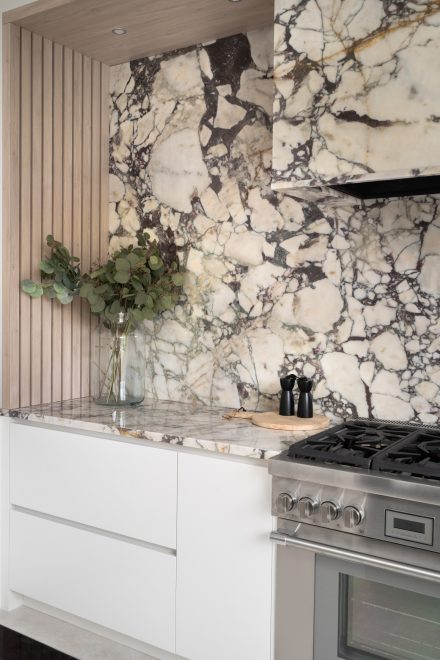 Kitchen with an island and cabinets enbeded in a stone wall  Ateliers Jacob