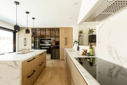 Contemporary kitchen design with black central island and white built-in cabinets.