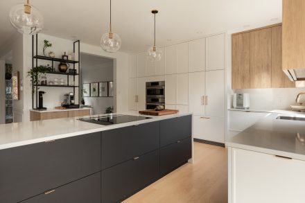 Modern kitchen with central island and suspended lighting.