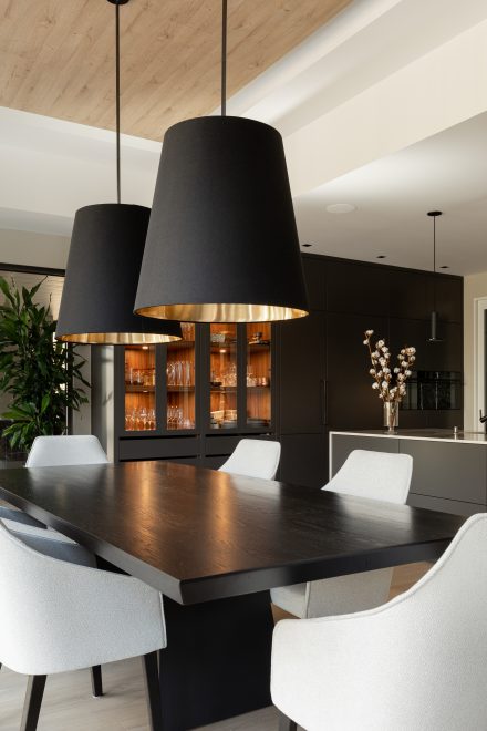 Une salle à manger avec une table en bois gris foncé et luminaires suspendus