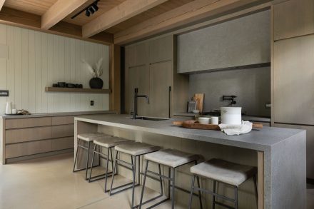 U-shaped kitchen with central island and open storage in the background.