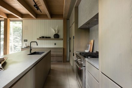Modern white kitchen furniture with island and dark stone countertop.