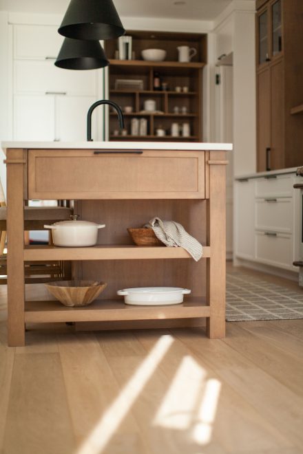 Une cuisine farmhouse avec îlot central en bois et des armoires blanches.