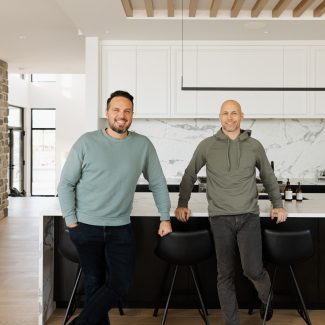 Simon Bouchard et Steve Bégin, joueur de hockey professionnel , dans sa cuisine conçue par Ateliers Jacob avec des armoires noires en bois et un grand îlot central. 