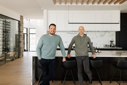 Simon Bouchard et Steve Bégin, joueur de hockey professionnel , dans sa cuisine conçue par Ateliers Jacob avec des armoires noires en bois et un grand îlot central.