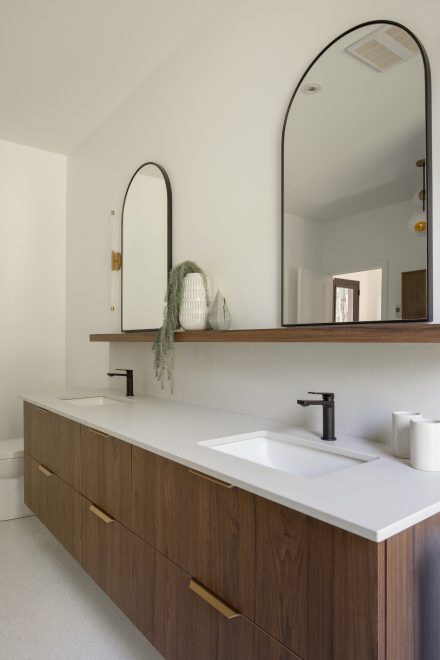 Custom made vanity with dark wood, floating shelf and arched mirors