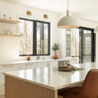 Kitchen with an island with seated places and windows facing the forest. 