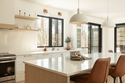 Kitchen with an island with seated places and windows facing the forest.