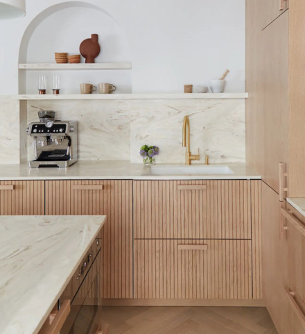 Cuisine parisienne avec matériaux mixtes : laiton, plâtre, chêne naturel et comptoirs en Corian au fini mat et raffiné.
