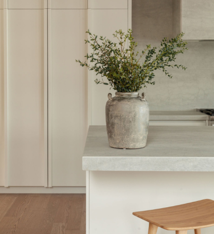cuisine épurée avec comptoir en porcelaine Laminam couleur Pietra di Savoia Perla et armoires crème intégrées.