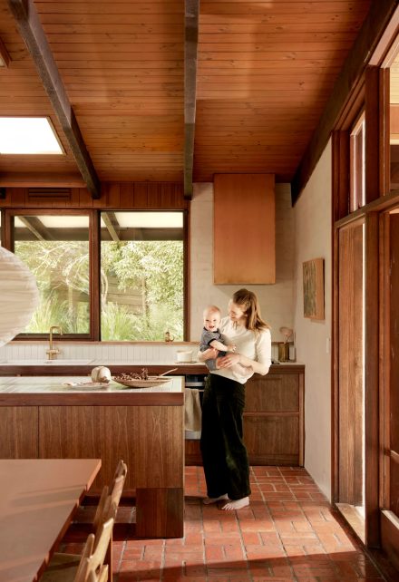 Îlot central en bois dans une cuisine Mid-Century moderne, conçu par Adriana Hanna, avec plafond en lattes de bois et plancher en brique terracotta.
