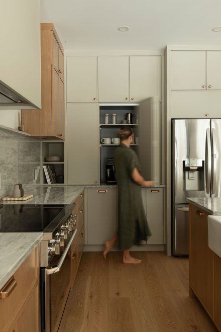À proximité du réfrigérateur dissimulé, un coin café se découvre comme une niche raffinée. Derrière des portes intégrées, une station complète prend place : une machine à espresso, des tasses et des accessoires parfaitement rangés. Cet espace bien pensé libère la surface de travail principale, transformant la routine matinale en une expérience minutieusement orchestrée.