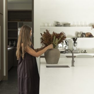 Cuisine Ateliers Jacob avec îlot clair, bois naturel et bouquet végétal, illustrant les tendances couleurs 2026 inspirées de la nature.