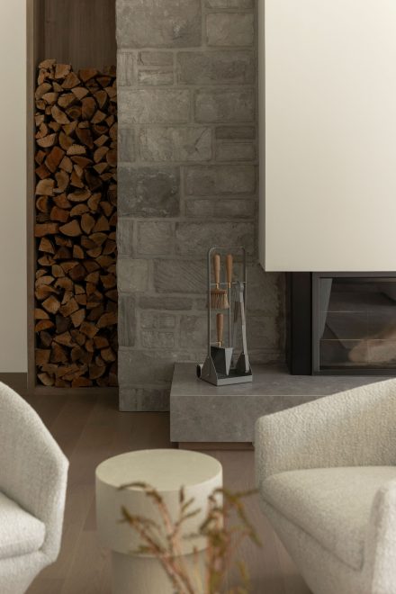 Foyer contemporain en pierre naturelle avec rangement à bois intégré, mobilier et aménagement intérieur signés Ateliers Jacob