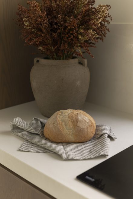 Pain frais posé sur un comptoir, texture de la croûte et calme d’un geste simple lié au rituel de cuisiner.