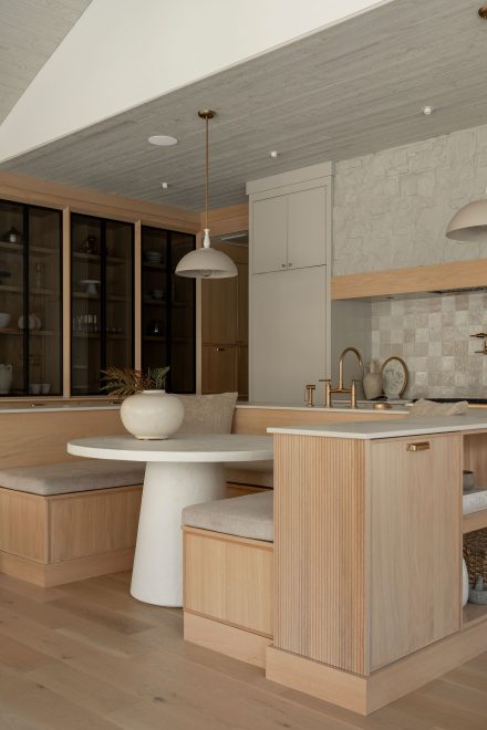Banquette intégrée à l’îlot, dans une cuisine sur mesure Ateliers Jacob aux volumes calmes et aux matières naturelles.