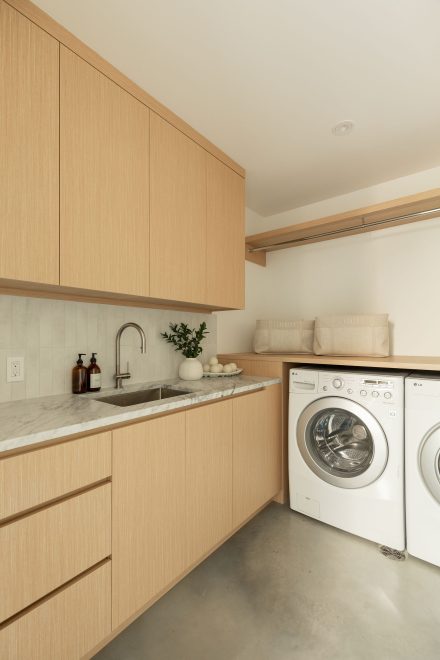 Mudroom sur mesure en bois clair avec banc intégré et tablette d’angle pour rangement de chaussures, plancher en motif chevron.