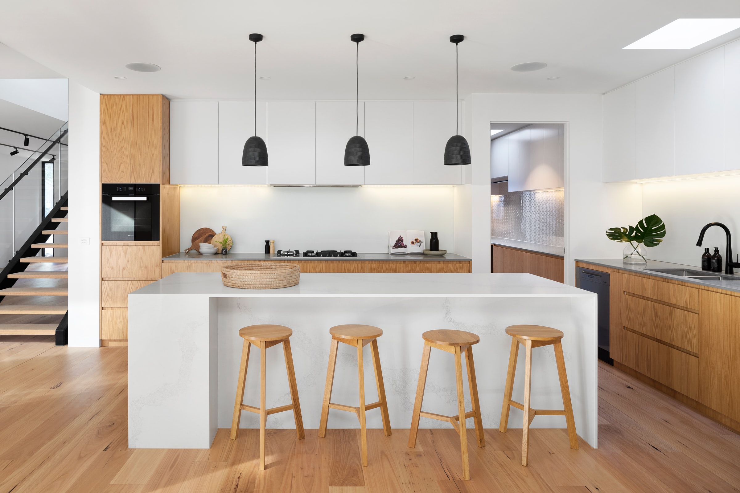 Simple and refined Scandinavian-style cuisine. The cabinets and stools are made of wood, the counter is white.