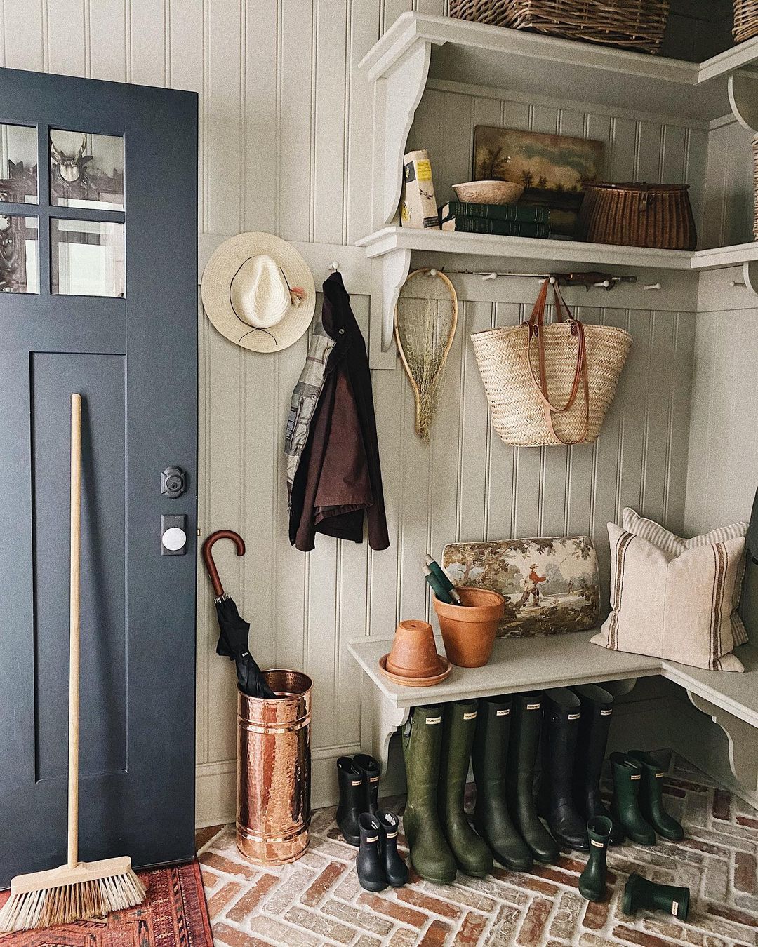 Mudroom dans une maison de campagne avec quelques étagères, des portants pour les sacs et manteaux et un espace pour ranger les bottes.